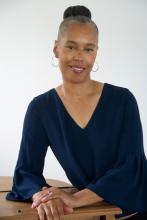 Dr. Banks poses in a navy blouse with a high bun